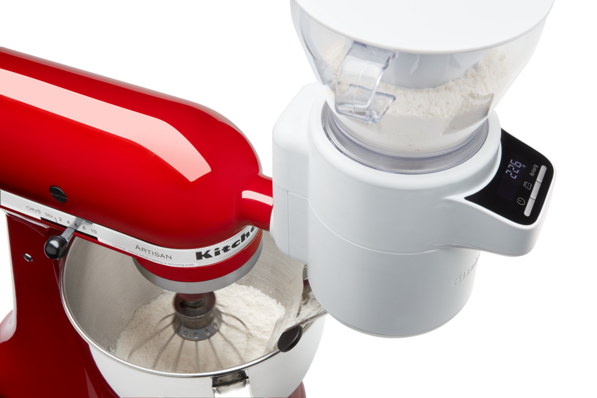 Ein roter KitchenAid-Mixer mit einem weißen Mehlmahlaufsatz. Mehl ist im Mixer sichtbar.