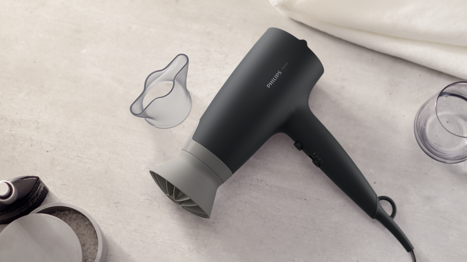 Black and gray hair dryer with attachments on a light surface.