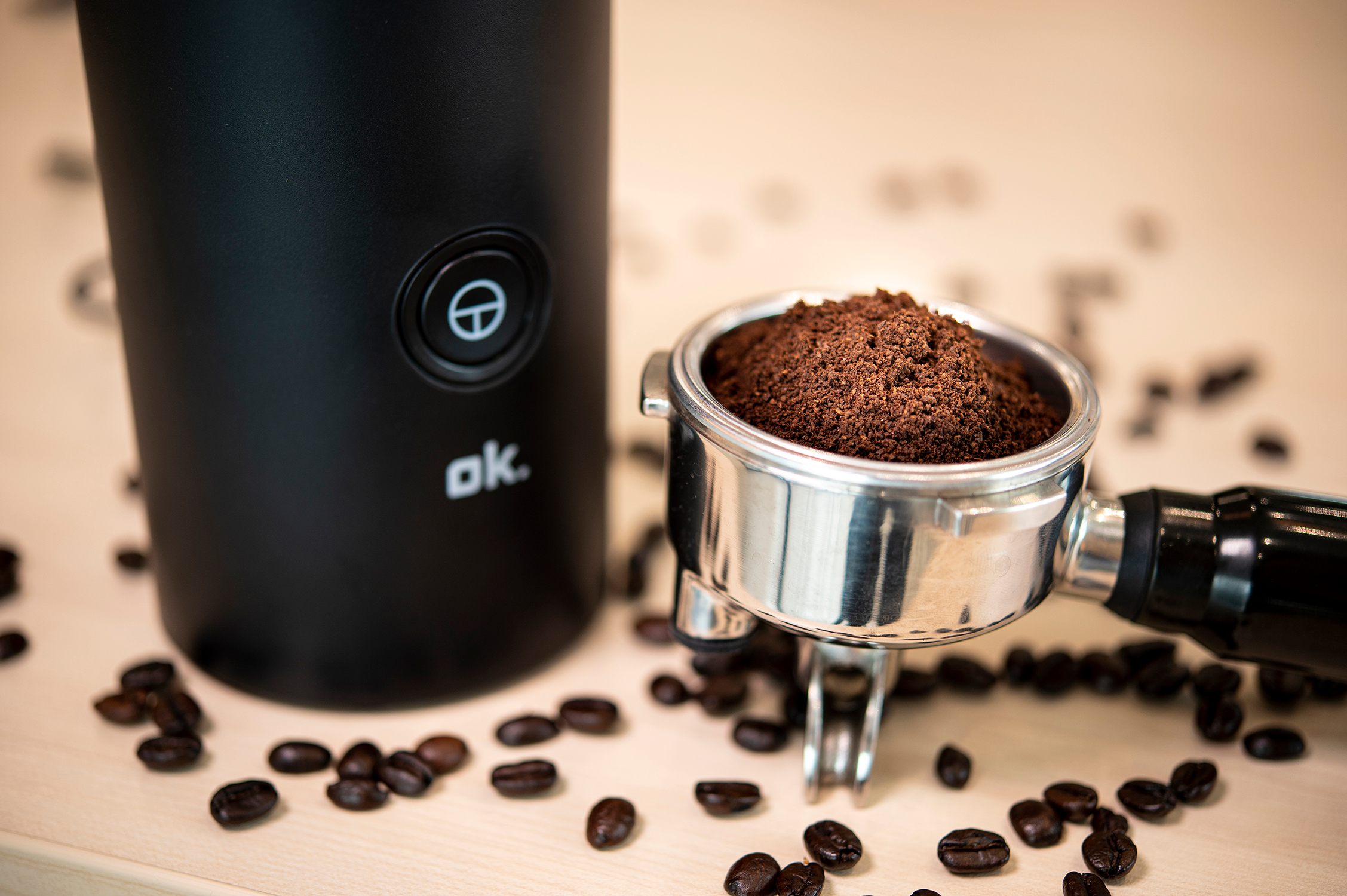 A coffee grinder with ground coffee in the portafilter, surrounded by coffee beans.