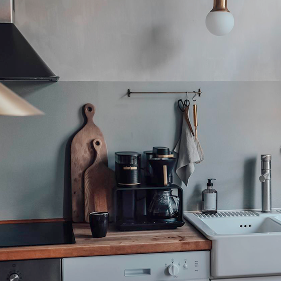 Scène de cuisine avec une cafetière, des planches à découper en bois et un évier.