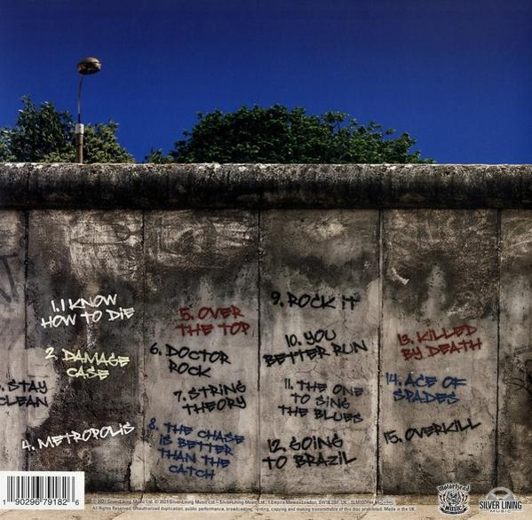 Album borító a berlini fal graffitijével. Tartalmaz dalszövegeket és egy zenekar logóját. Kék ég a háttérben.