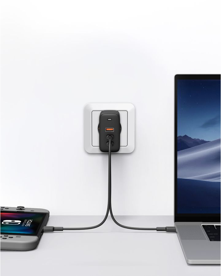 Un caricabatterie collegato a una presa a muro, che carica un laptop e uno Switch.