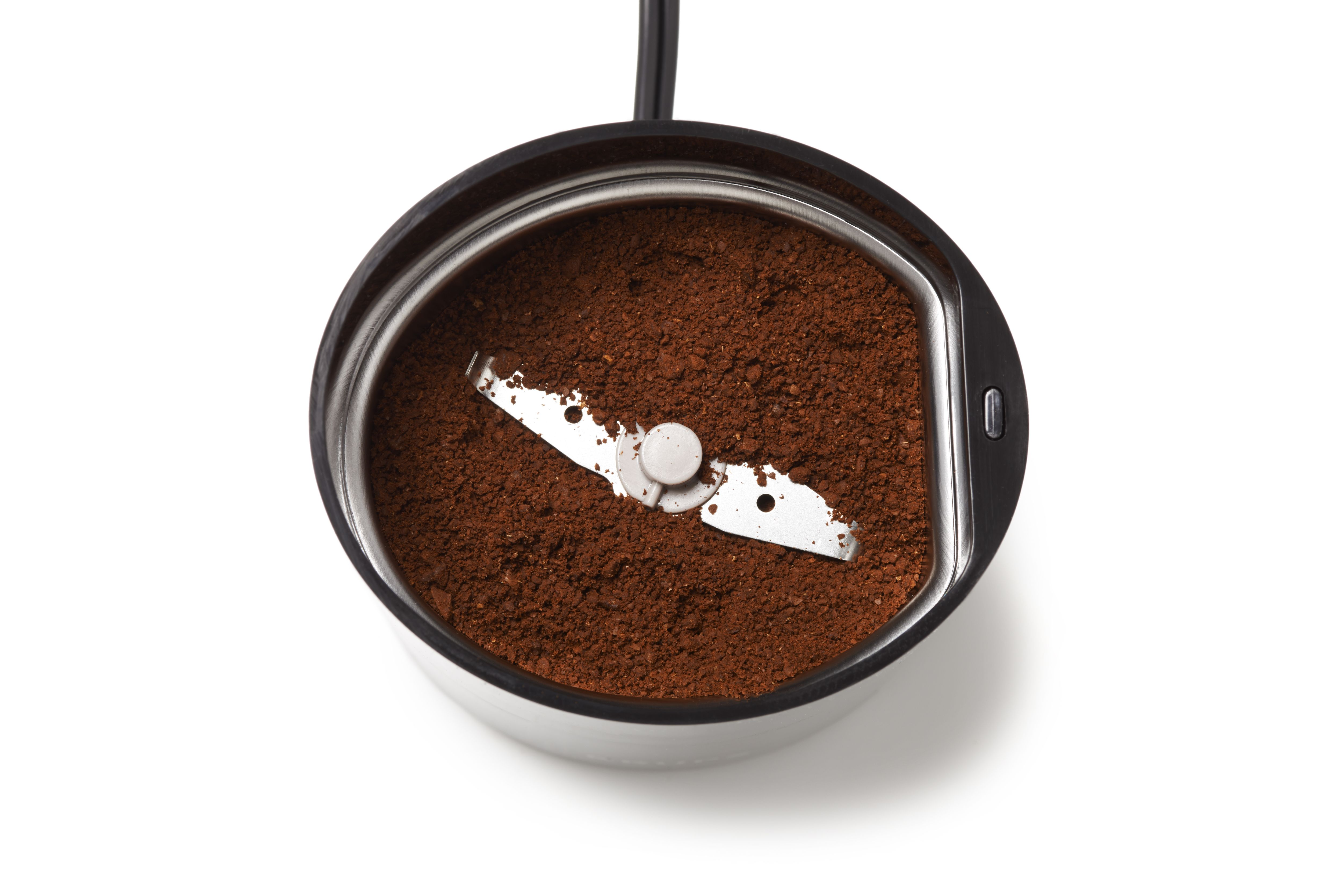 Kaffeemühle, Draufsicht, enthält gemahlenen Kaffee. Eine Klinge ist im Inneren sichtbar. Weißer Hintergrund.