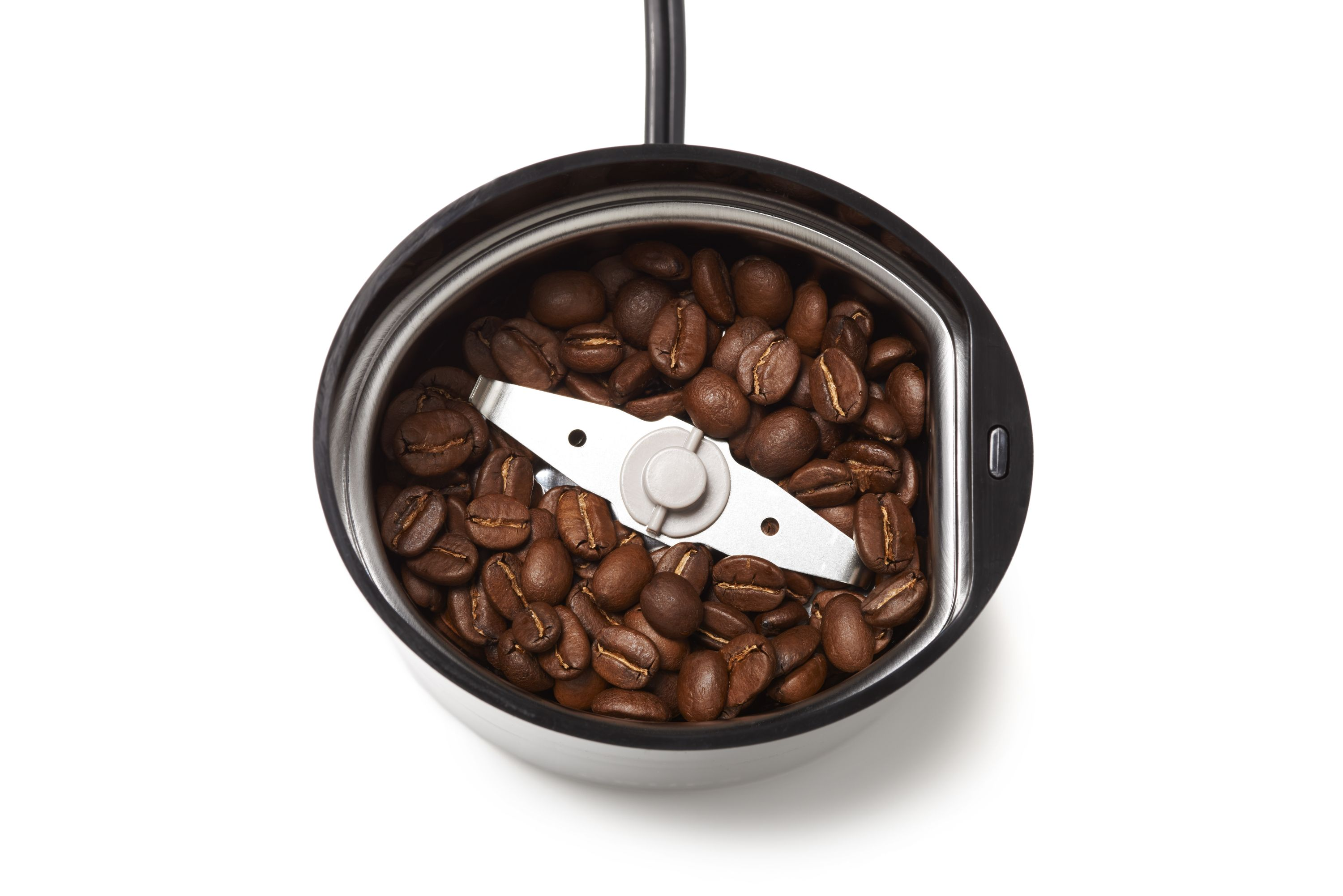 Kaffeemühlen-Innenraum. Kaffeebohnen liegen in der Mitte. Eine silberne Klinge ist sichtbar.