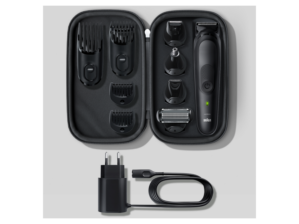 Un kit de aseo negro con cabezales de recortadora y cargador sobre un fondo gris.