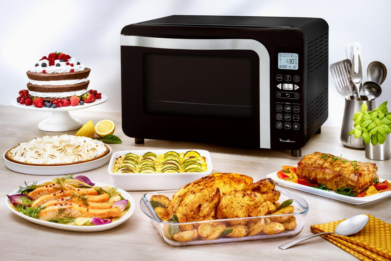 Black microwave oven with various dishes of food, including cake and roasted chicken.