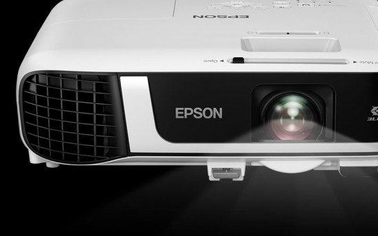 Fehér Epson projektor fekete részletekkel. Fekete háttér. Fénysugár látható.