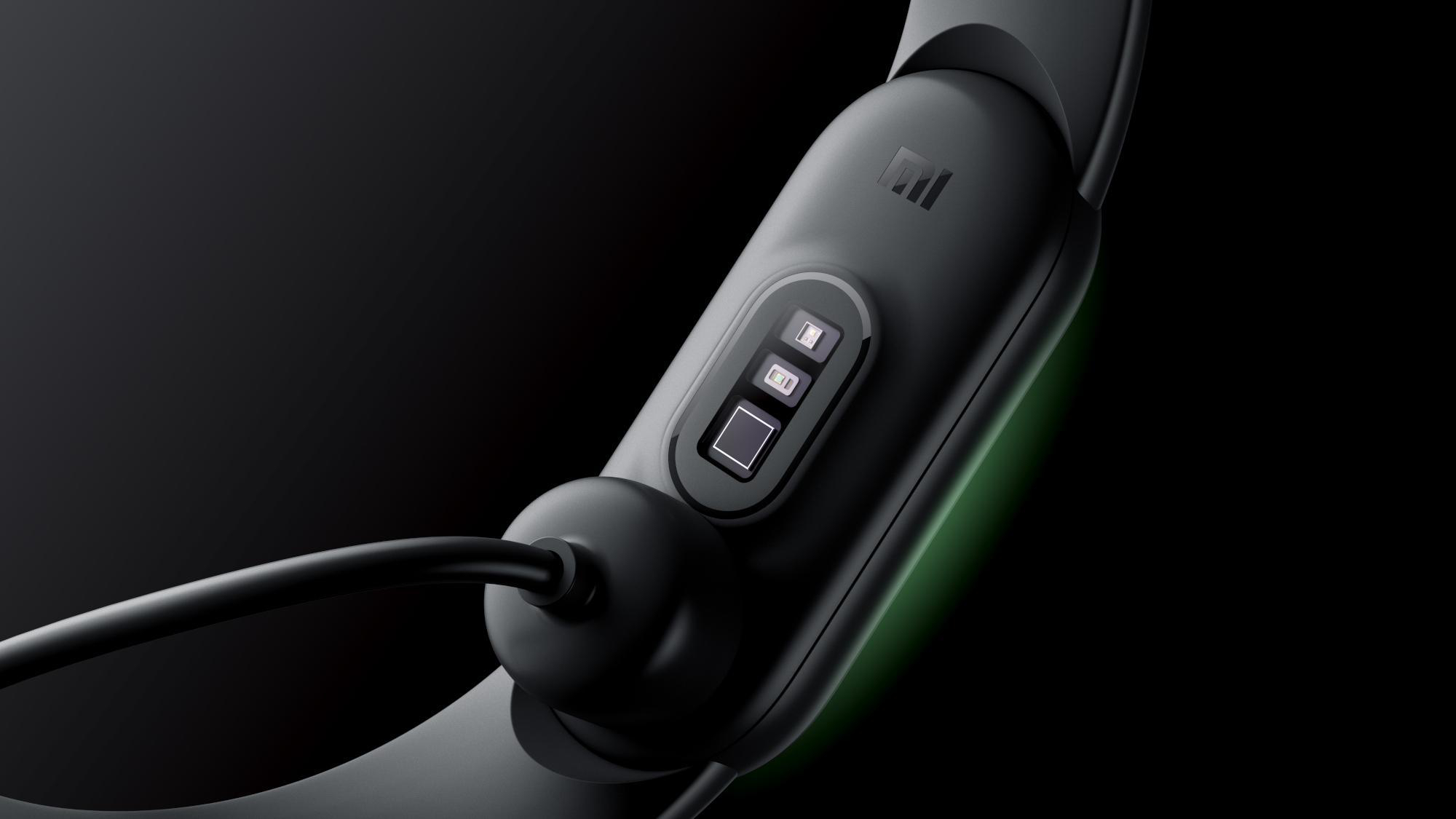 Schwarzer Fitnesstracker mit angeschlossenem Ladekabel. Dunkler Hintergrund.