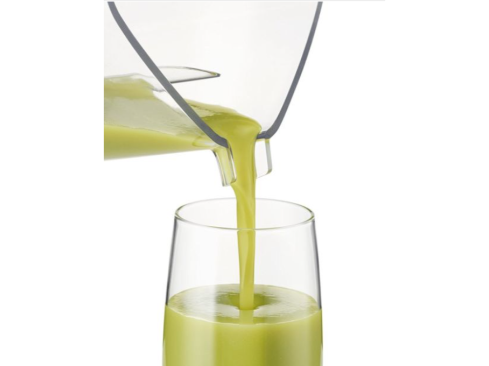 Líquido verde vertiéndose en un vaso alto y transparente desde una licuadora.
