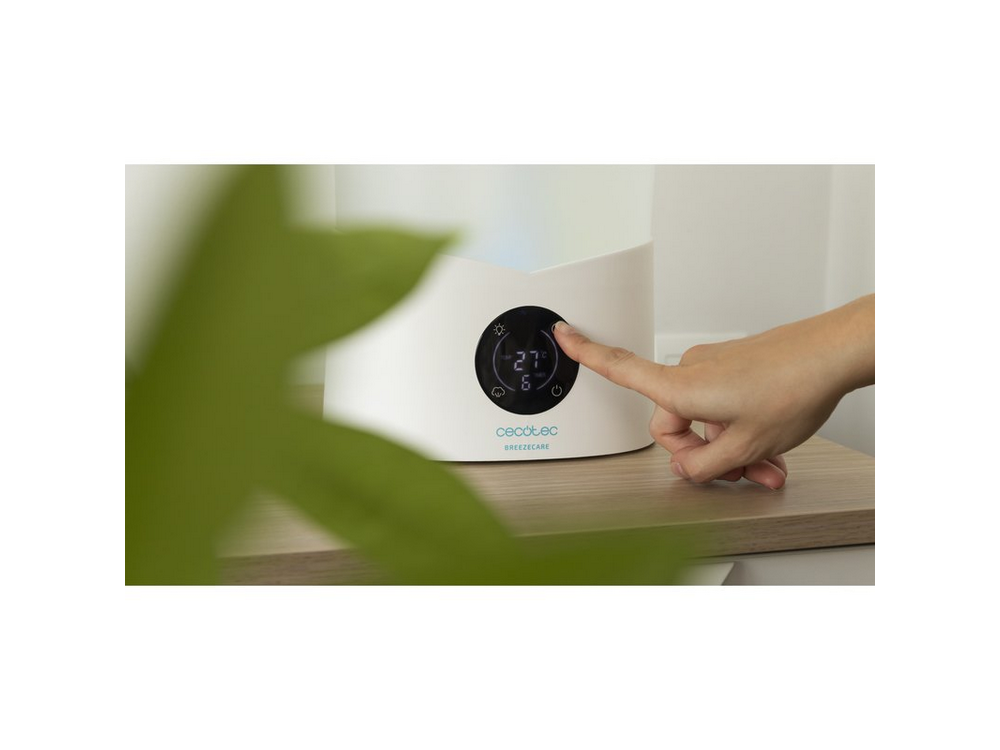 La mano de una persona presiona un botón en un humidificador blanco con pantalla. Hoja verde en la esquina.