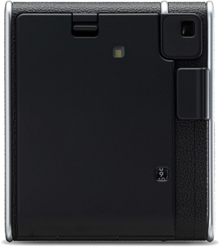 Achterkant van een zwarte instantcamera met zilveren rand. Voorzien van flitser en deur.
