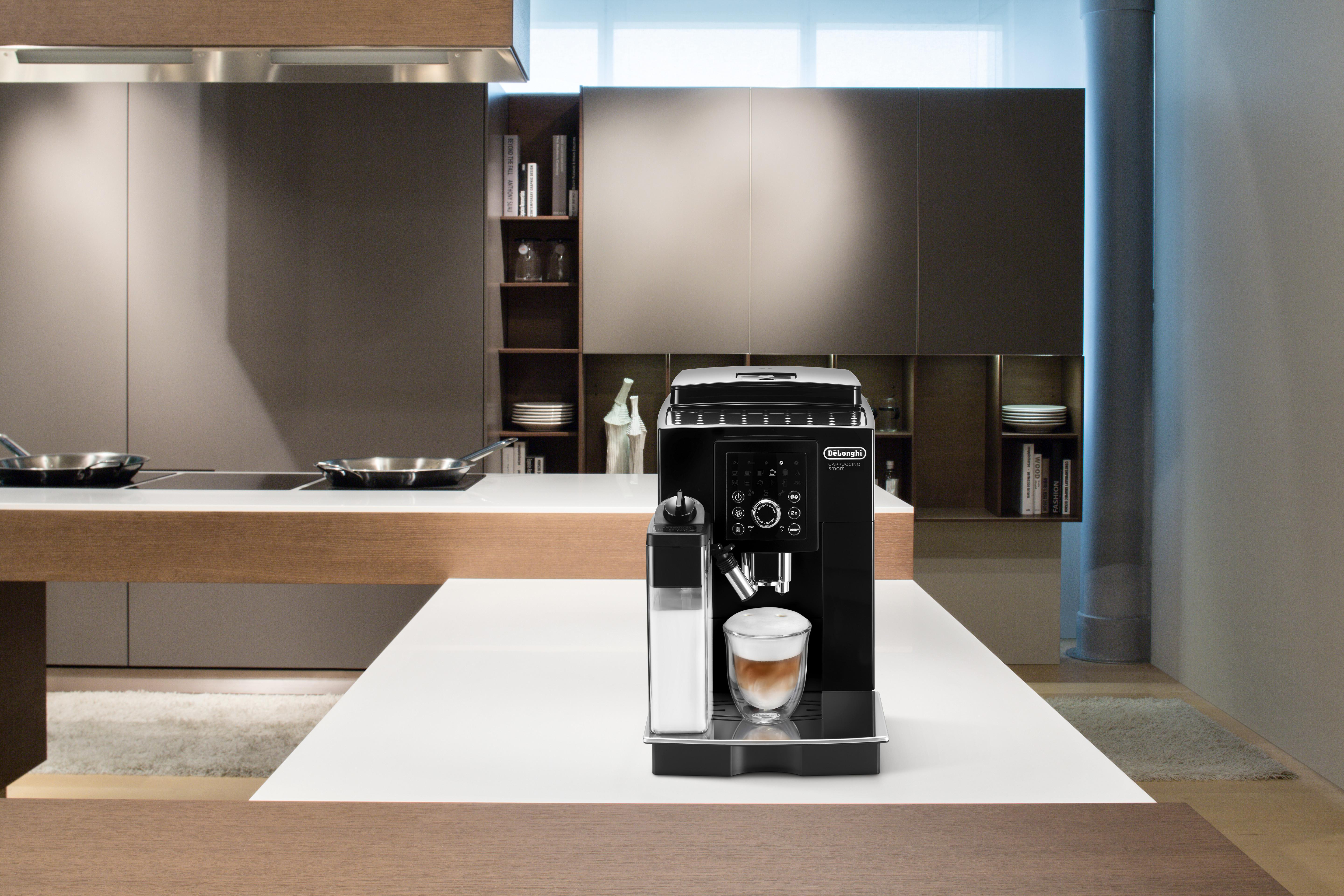 Eine schwarze Kaffeemaschine auf einer weißen Theke. Eine Küchenszene im Hintergrund.