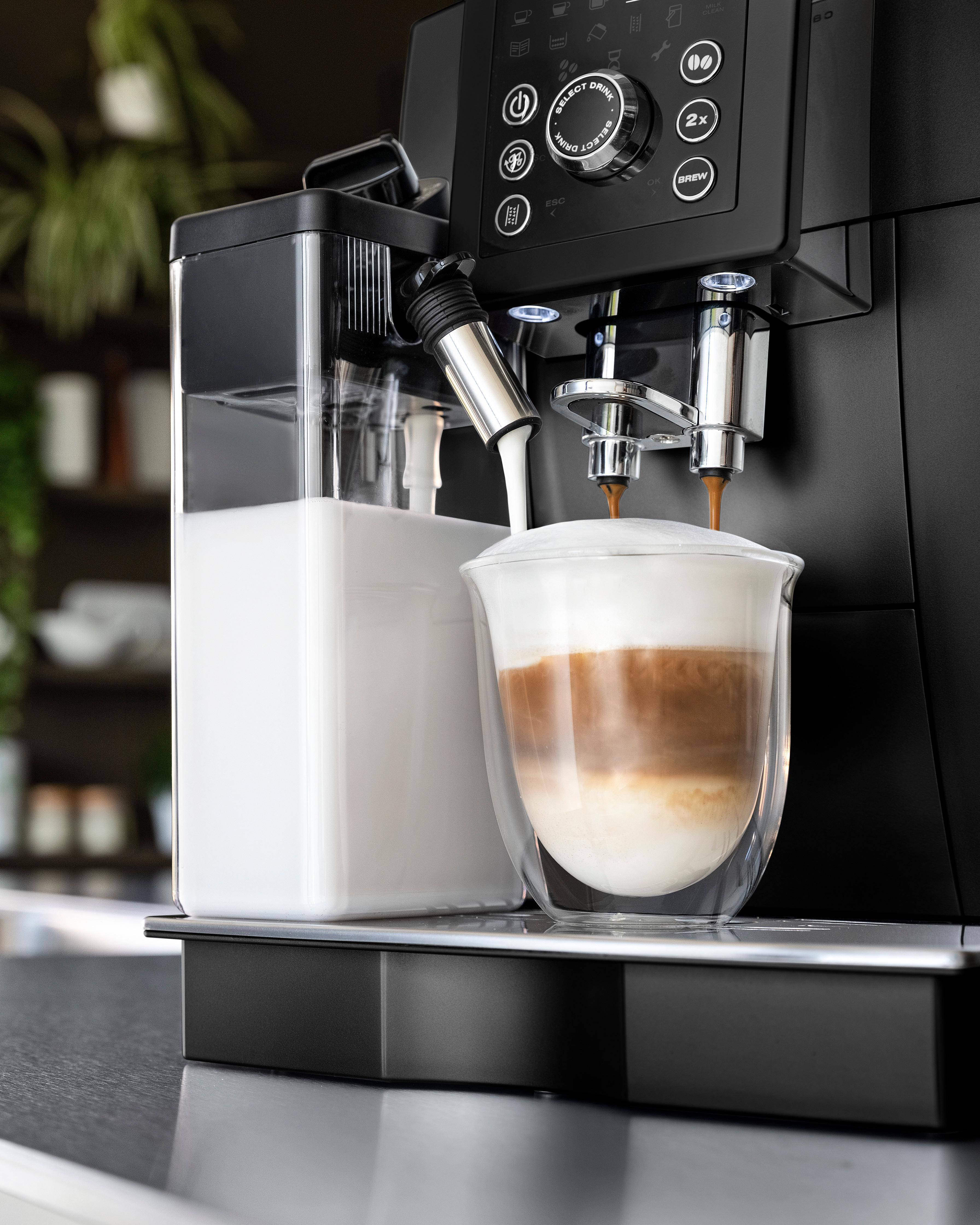 Espressomaschine, die ein geschichtetes Getränk zubereitet. Milch und Espresso werden in ein Glas gegossen.