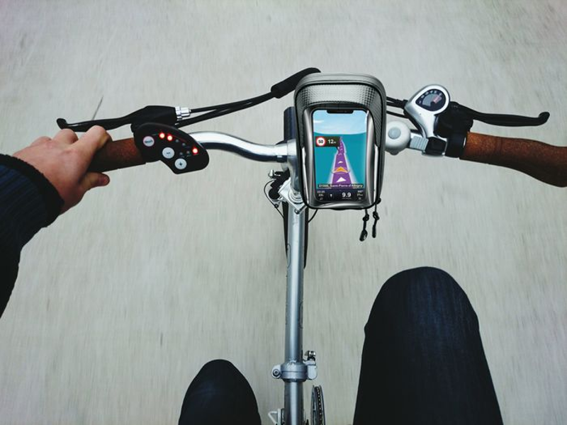 Ciclista che usa il telefono sul manubrio, mostrando la navigazione, su una strada.