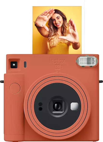 Orange Instax SQ1 Kamera mit Foto. Eine Frau rahmt ihr Gesicht mit ihren Händen ein.