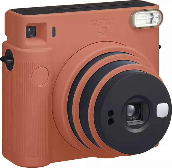 Eine orangefarbene Sofortbildkamera Instax SQ1 mit schwarzem Objektiv und Blitz, leicht angewinkelt.