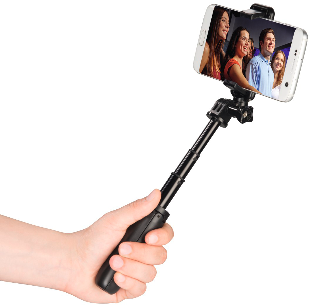 Mano che tiene un selfie stick con un telefono che mostra persone sorridenti.