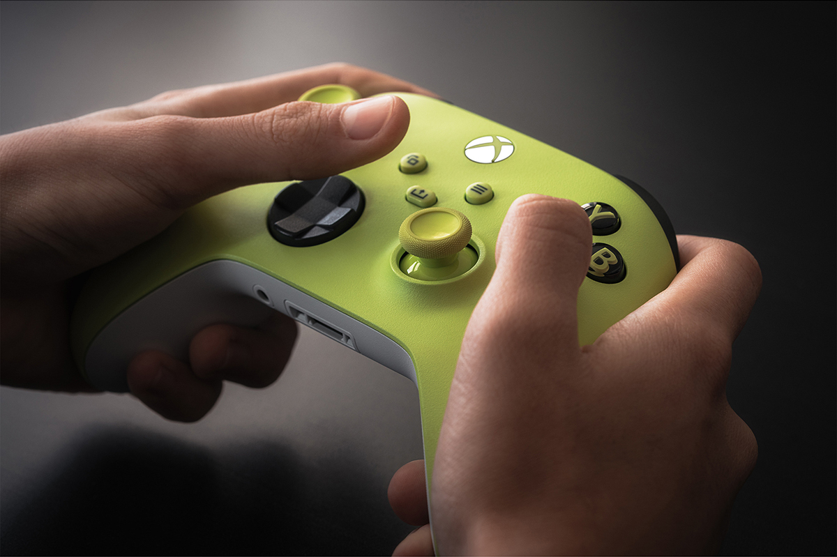 Hands holding a green Xbox controller, buttons visible, dark background.