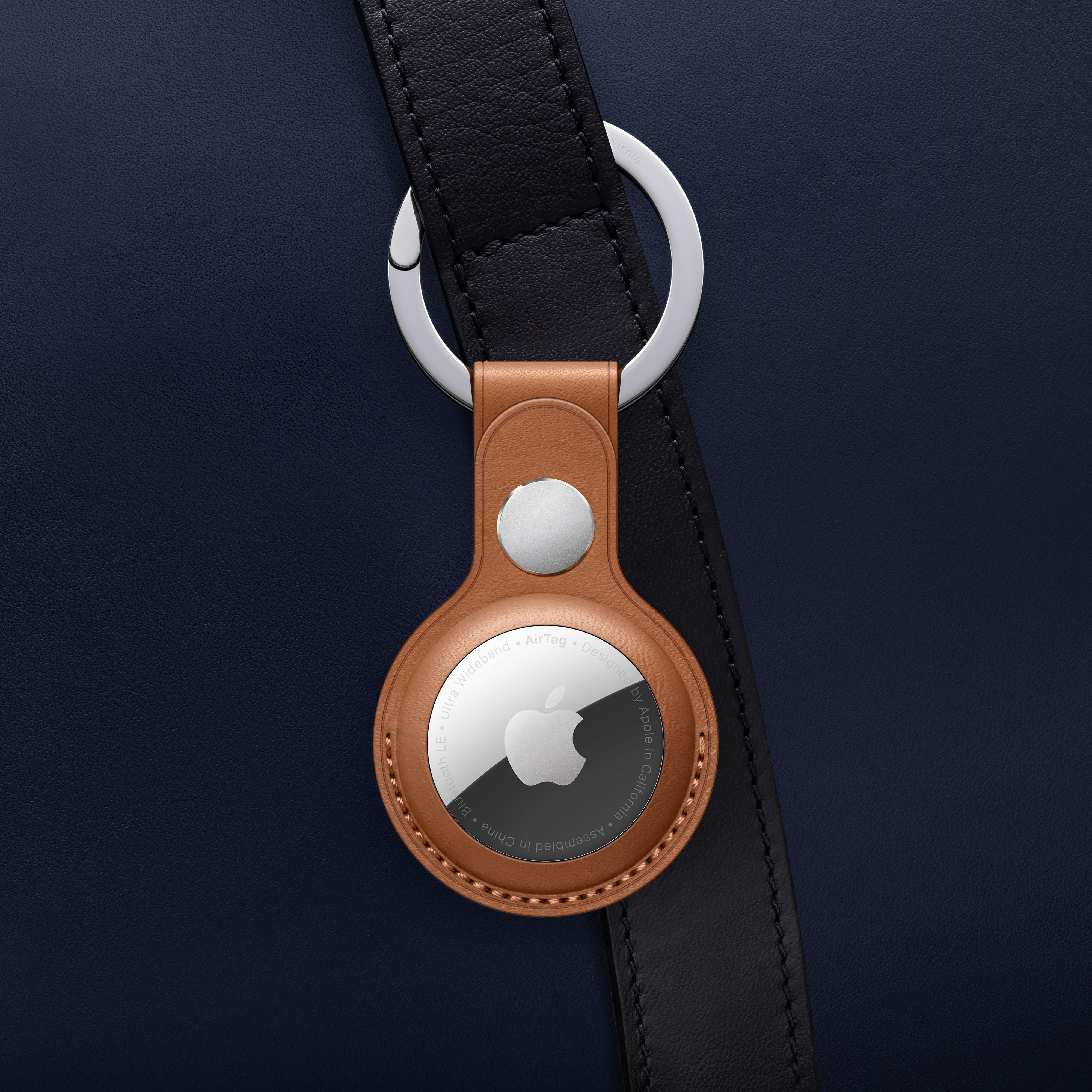 Apple AirTag an einem braunen Lederhalter, befestigt an einem schwarzen Gurt.