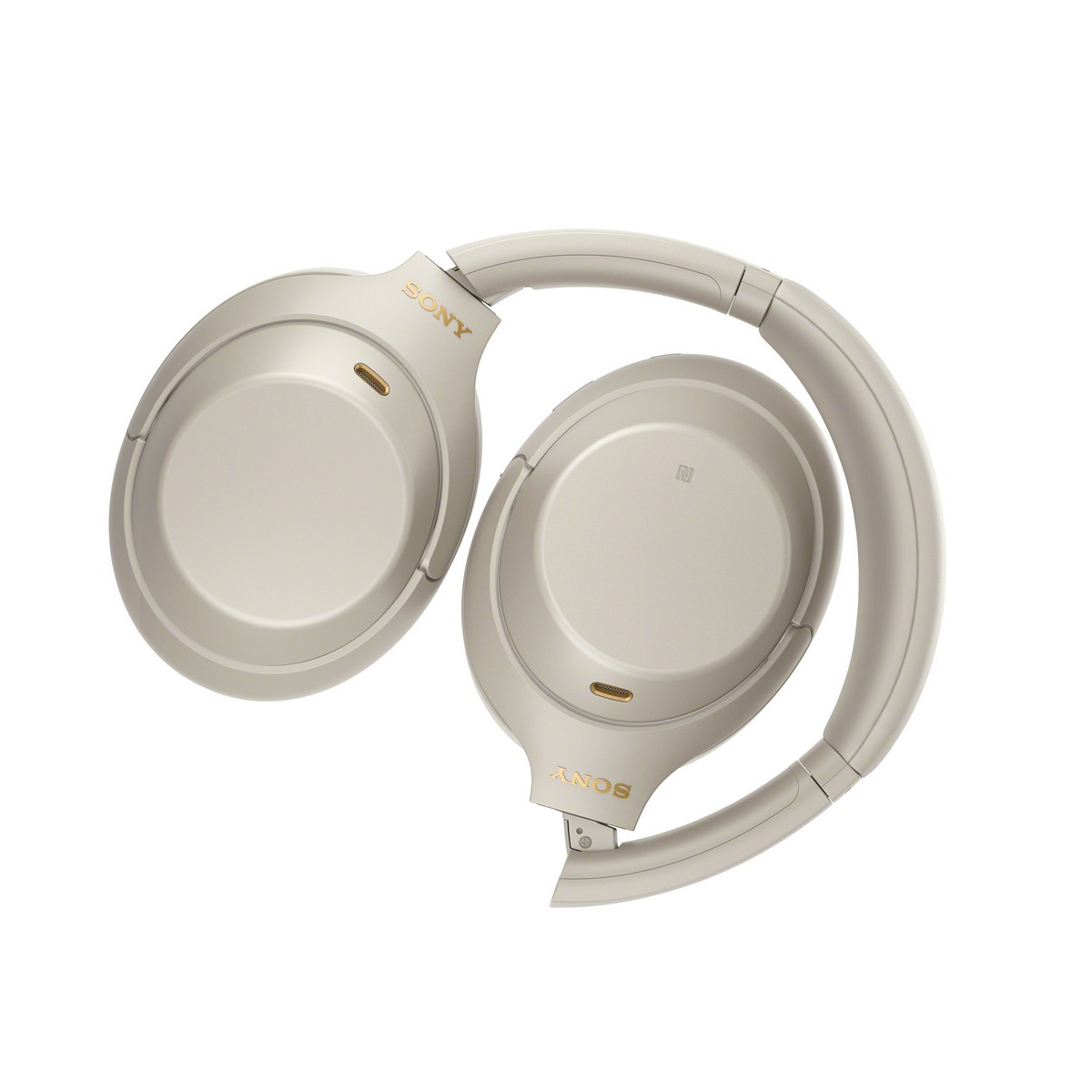 Auriculares Sony beige claro plegados sobre fondo blanco.