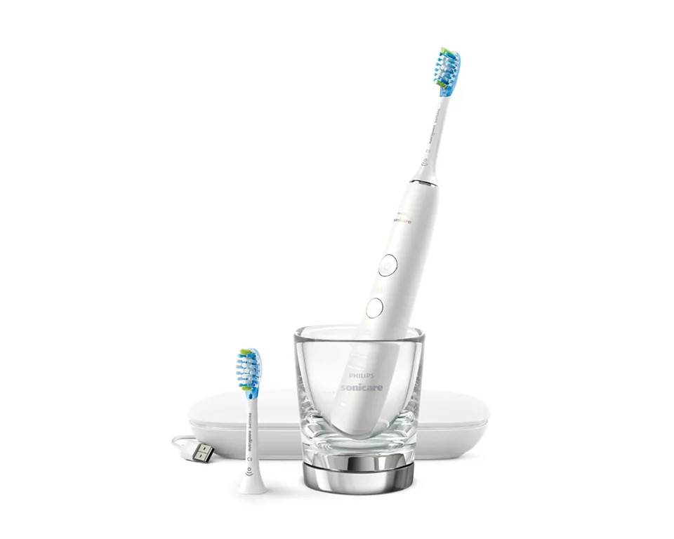 White Philips Sonicare toothbrush with charger and extra brush head in a glass.