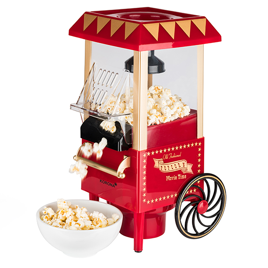 Rote und goldene Popcornmaschine mit herausfallendem Popcorn und einer Schüssel Popcorn. Weißer Hintergrund.