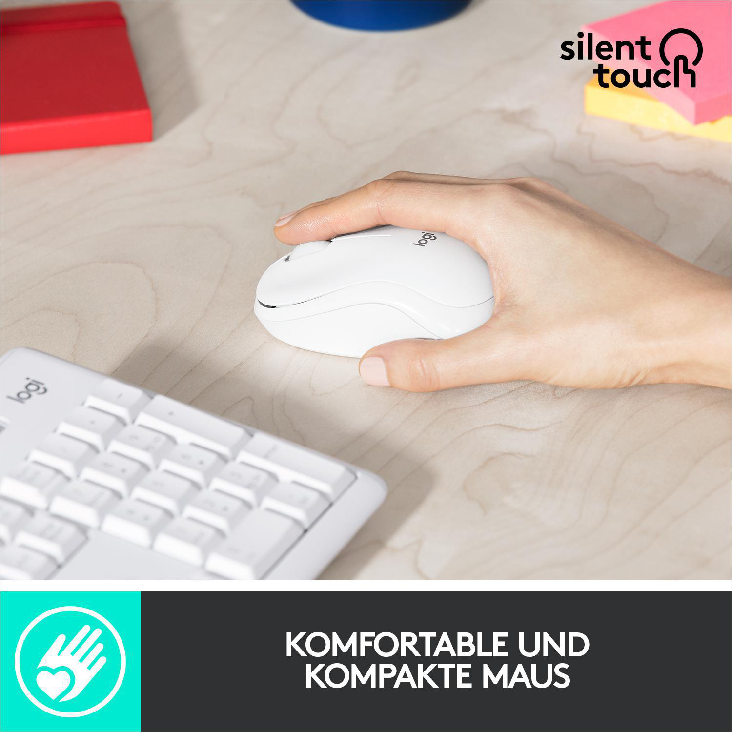 Eine Hand, die eine weiße Computermaus in der Nähe einer Tastatur hält. Der Hintergrund ist ein Holzschreibtisch.