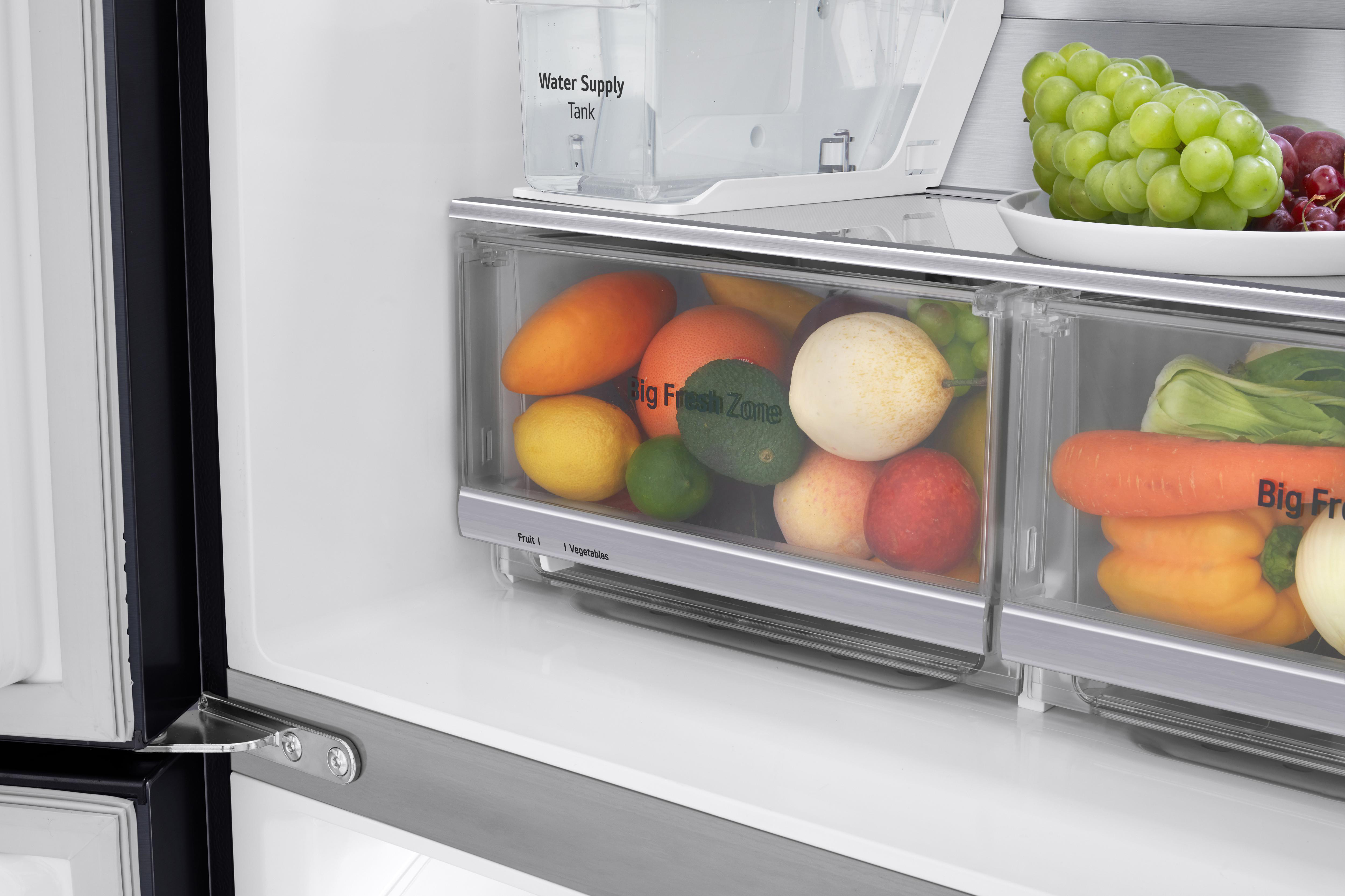 Geöffneter Kühlschrank mit Obst und Gemüse in transparenten Schubladen.
