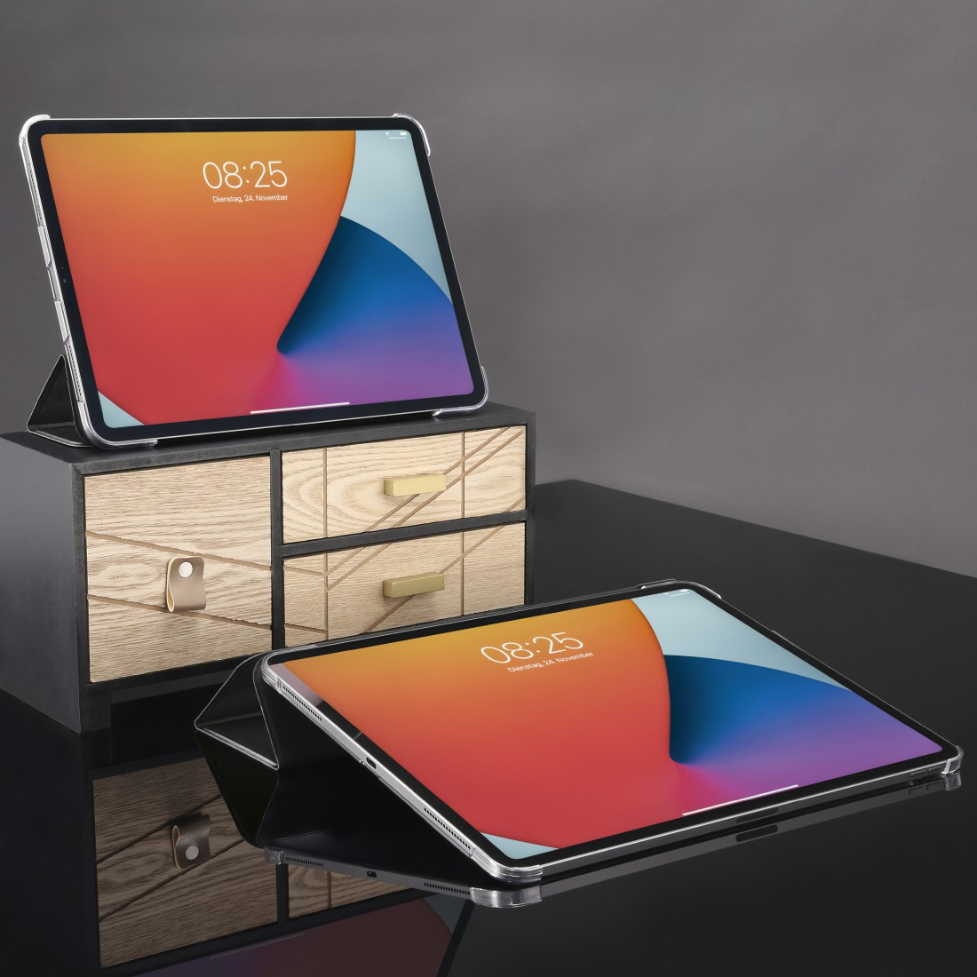 Zwei iPads auf einem Holzständer und schwarzer, reflektierender Oberfläche. Der Bildschirm zeigt die Uhrzeit.