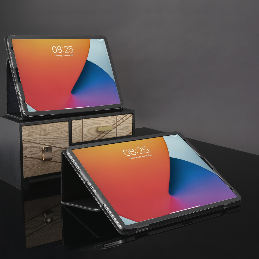 Zwei Tablets auf einem Schreibtisch. Eines oben, eines flach. Holzschublade im Hintergrund.