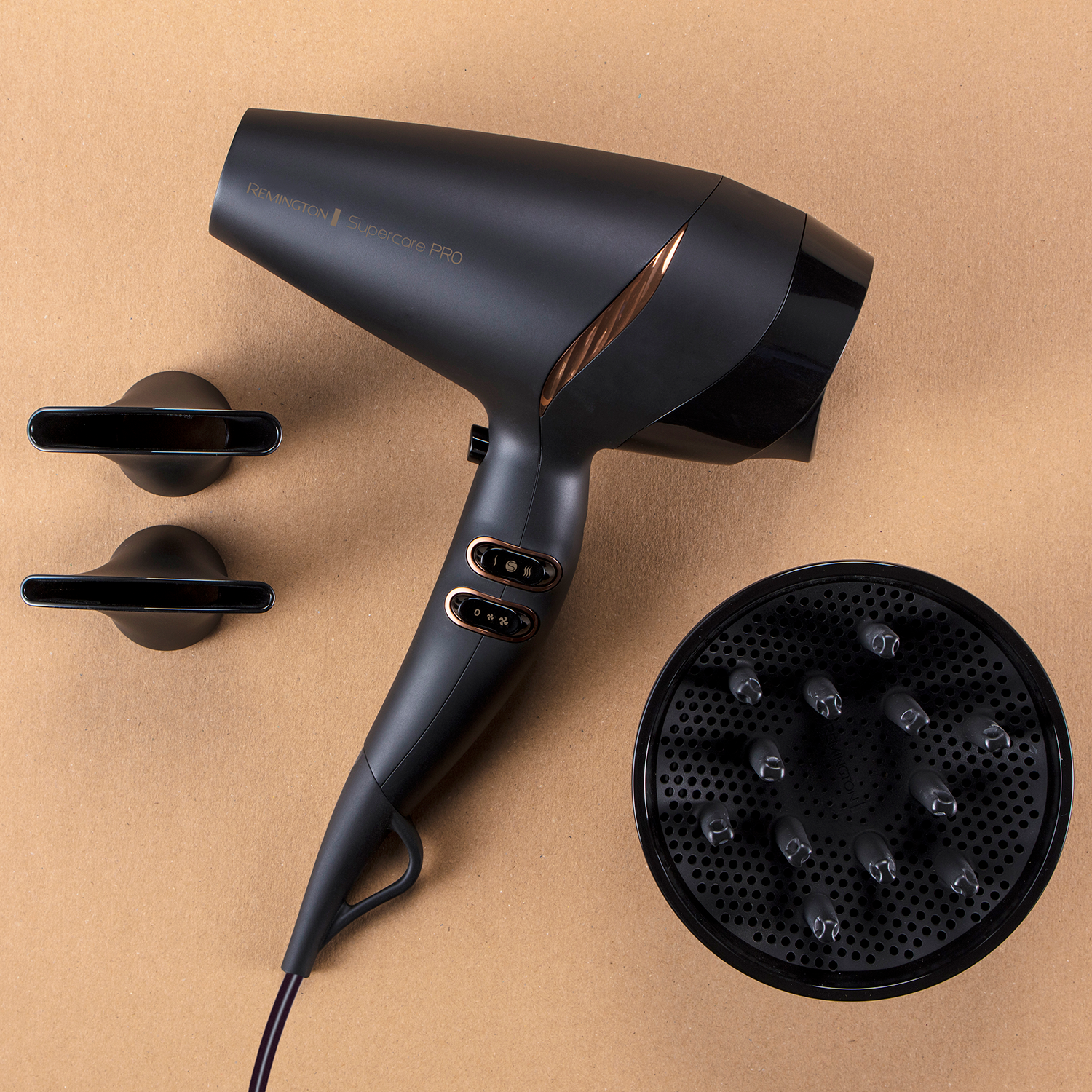Een zwarte Remington Supercare PRO föhn met opzetstukken op een bruin oppervlak.