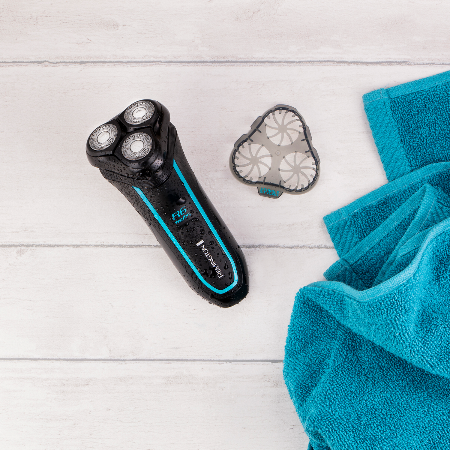 Electric shaver and a cleaning head on a white wooden surface with a blue towel.