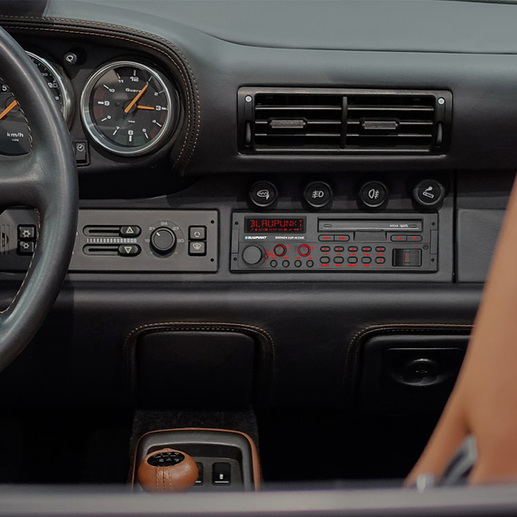 Intérieur d'une voiture classique avec détails du tableau de bord. Une radio Blaupunkt est visible.