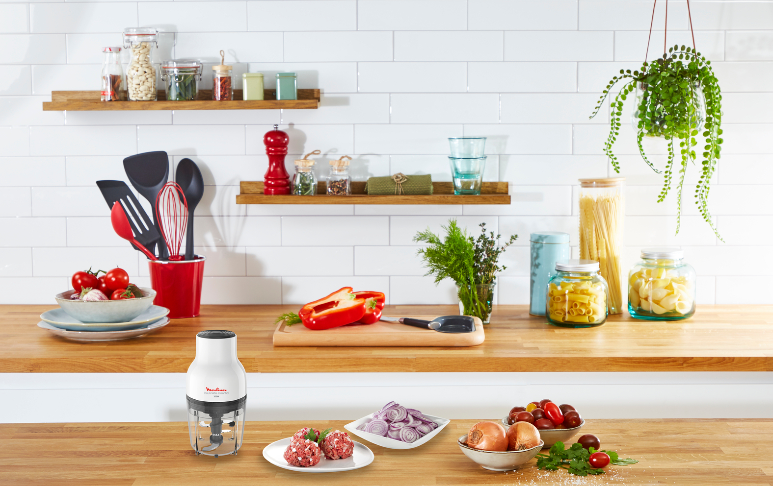 Une scène de cuisine avec un robot culinaire Moulinex sur un comptoir, avec des ingrédients et des ustensiles autour.