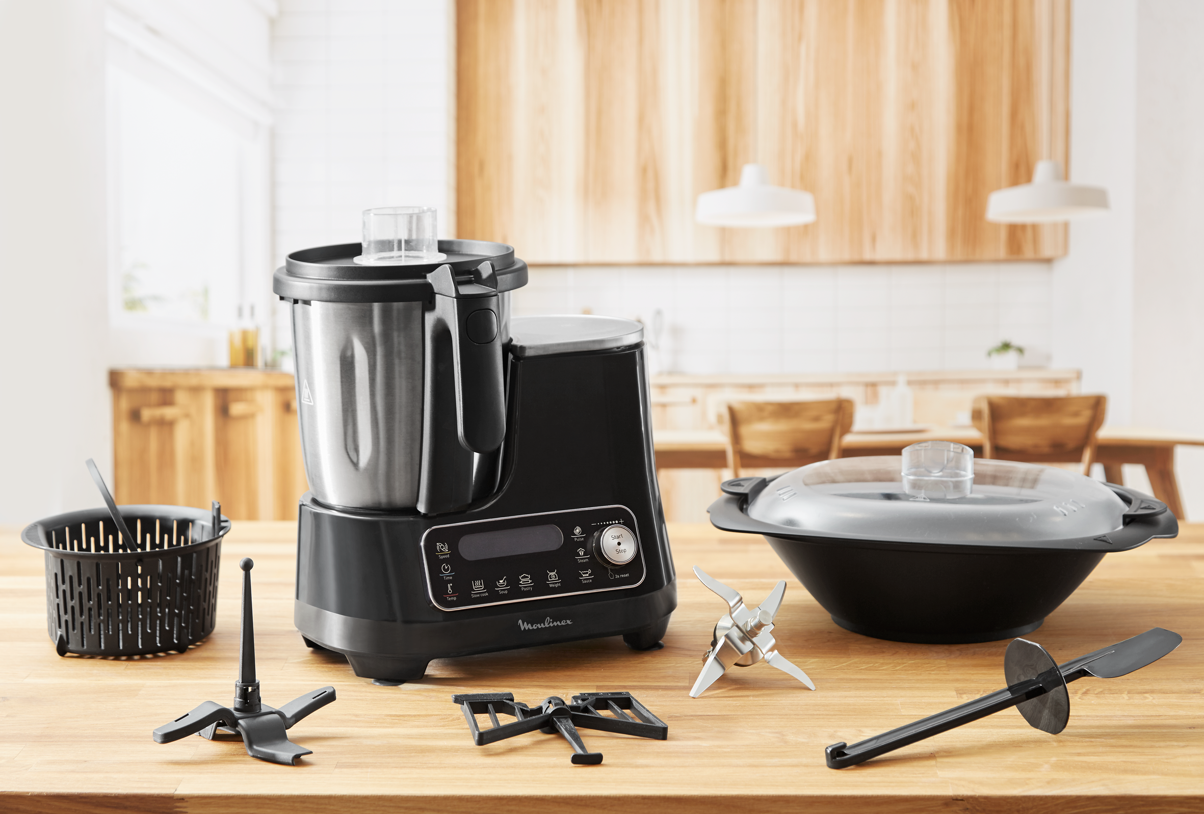 Robot de cuisine Moulinex avec accessoires sur table en bois, fond blanc.