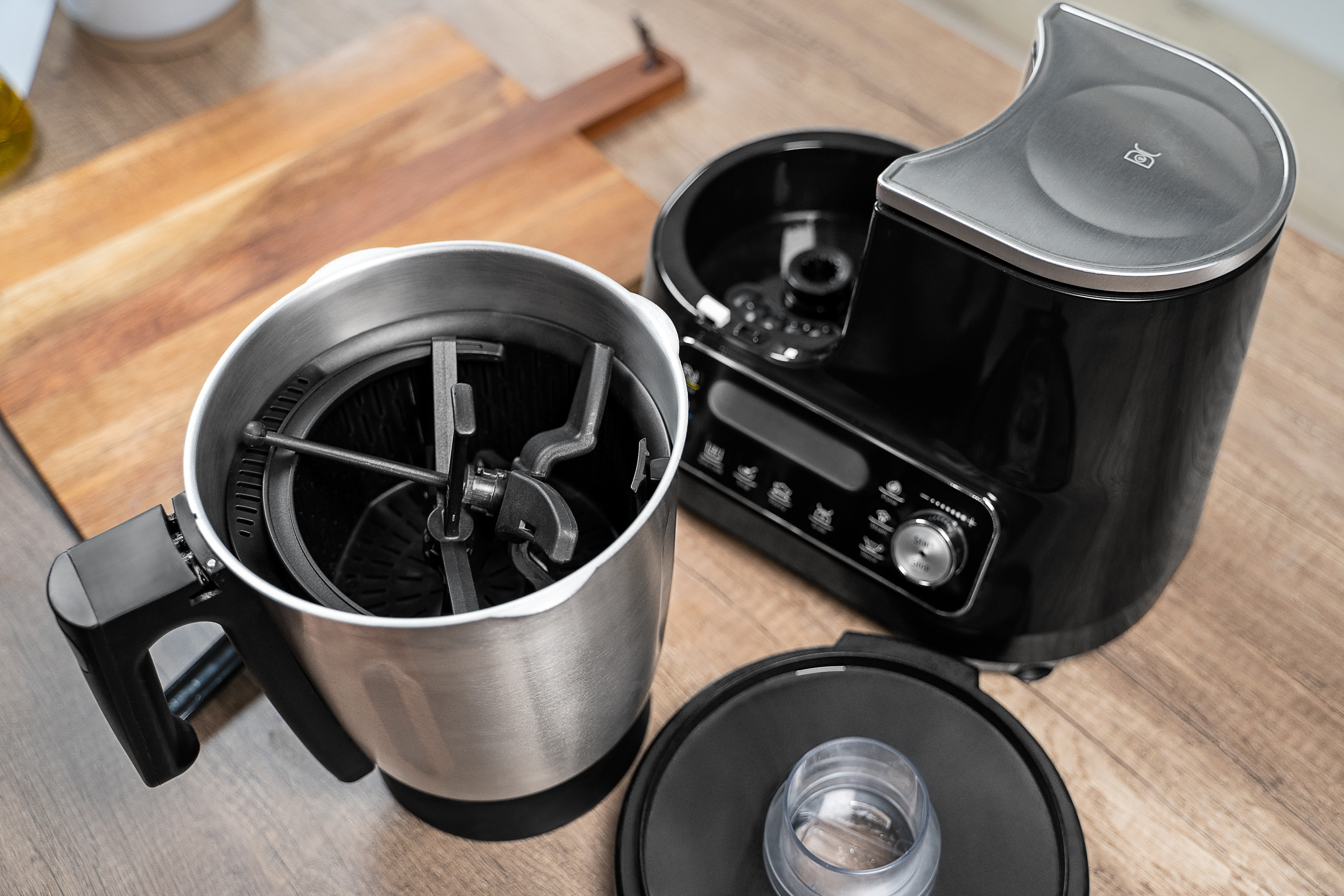 Un appareil de cuisine avec un corps noir, et des pièces détachées sur une surface en bois.