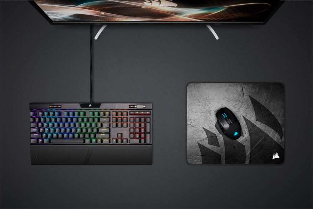 Clavier, souris et tapis de souris sur une surface gris foncé.