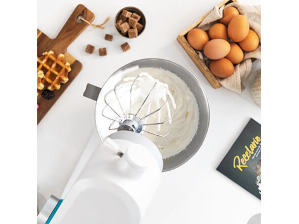 Una batidora con crema batida en un cuenco. También se ven gofres, huevos y terrones de azúcar.