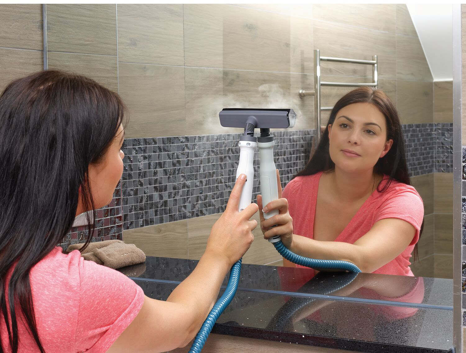 Vrouw maakt spiegel schoon met een stoomreiniger. De weerspiegeling van de vrouw is zichtbaar.