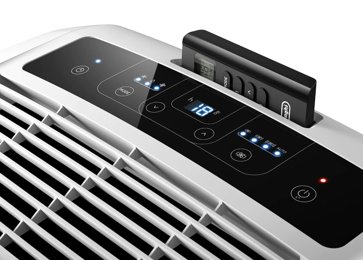 White and black air conditioner control panel. A remote control is docked on top.
