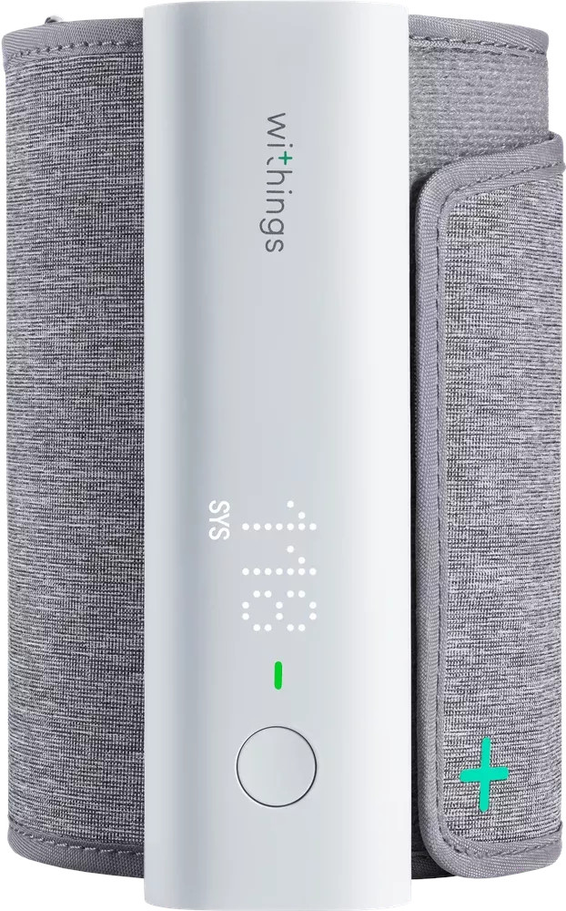 Un tensiomètre blanc de Withings. Il possède un affichage numérique indiquant des chiffres. Brassard gris fixé. Croix verte sur le brassard.