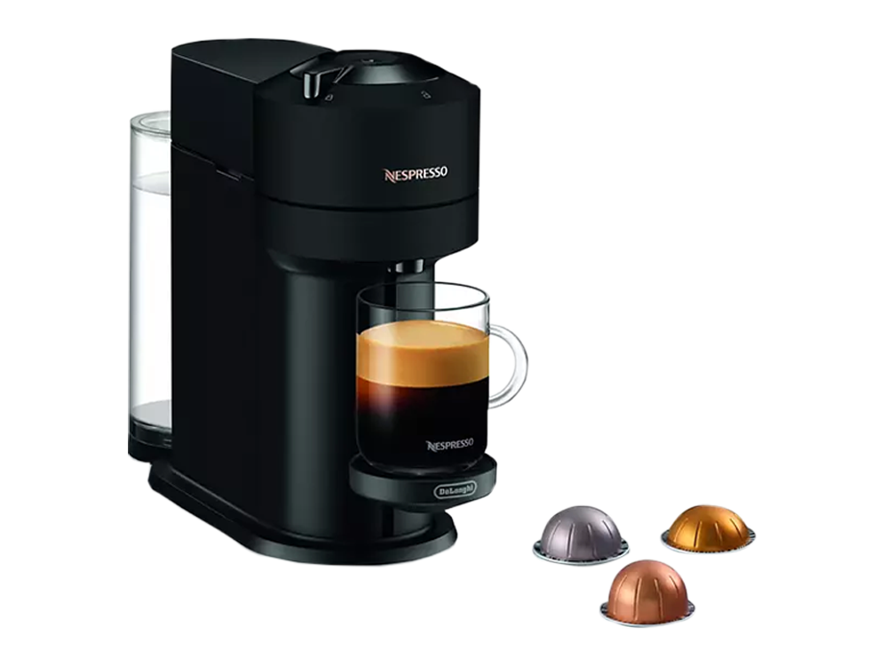 Una máquina Nespresso negra con café vertiéndose en un vaso, con cápsulas de café.