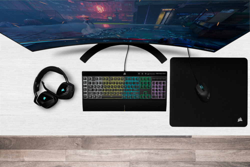 Van bovenaf gezien een gaming-opstelling met gebogen monitor, koptelefoon, toetsenbord en muis.