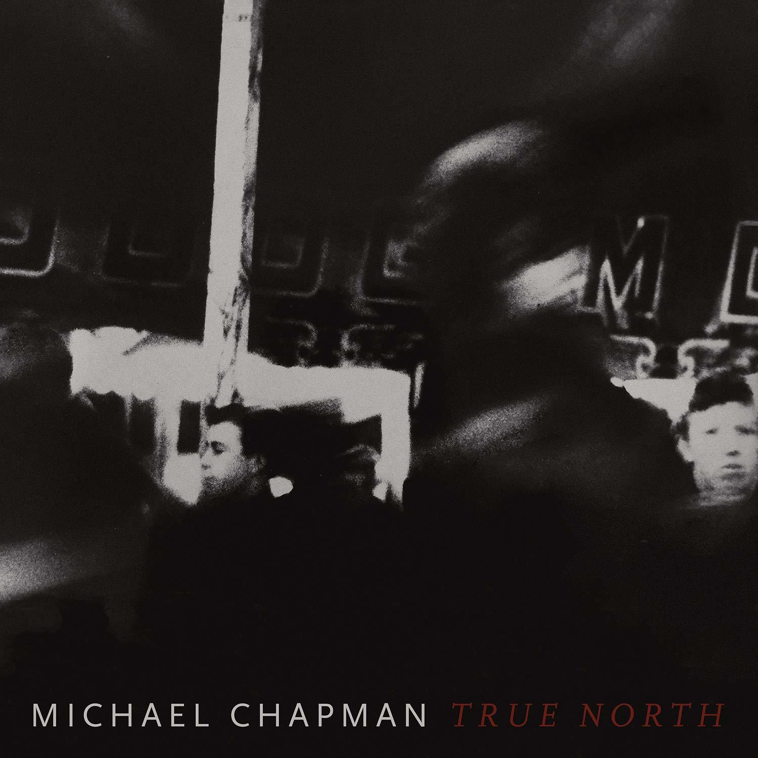 Zwart-wit afbeelding. Mensen in een vage omgeving. 'MICHAEL CHAPMAN' en 'TRUE NORTH' tekst.