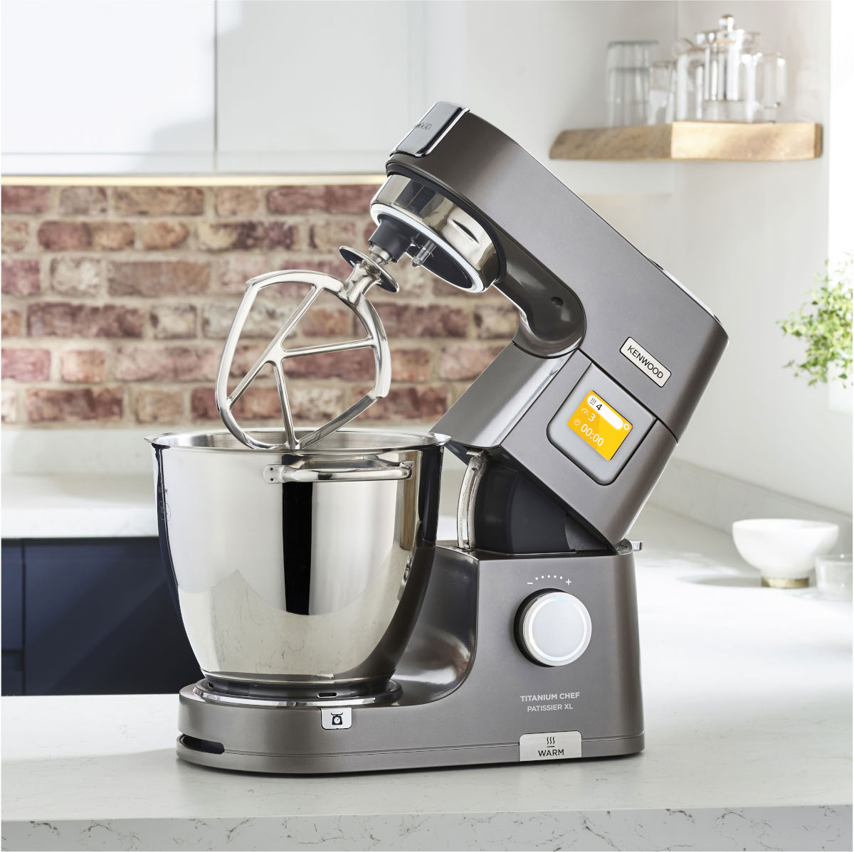 Grey Kenwood Titanium Chef Patissier XL kitchen mixer with a silver bowl and attachments.