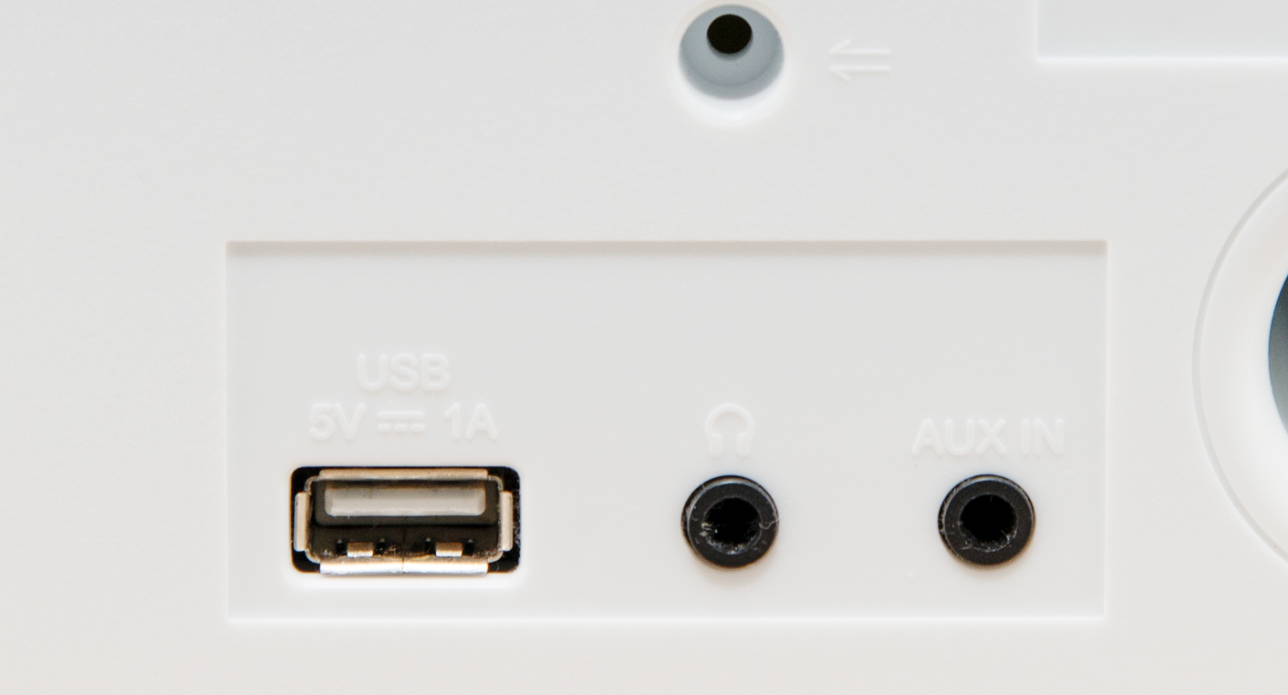 Nahaufnahme eines weißen Geräts mit USB-, Kopfhörer- und AUX IN-Anschlüssen. Die Anschlüsse sind beschriftet.
