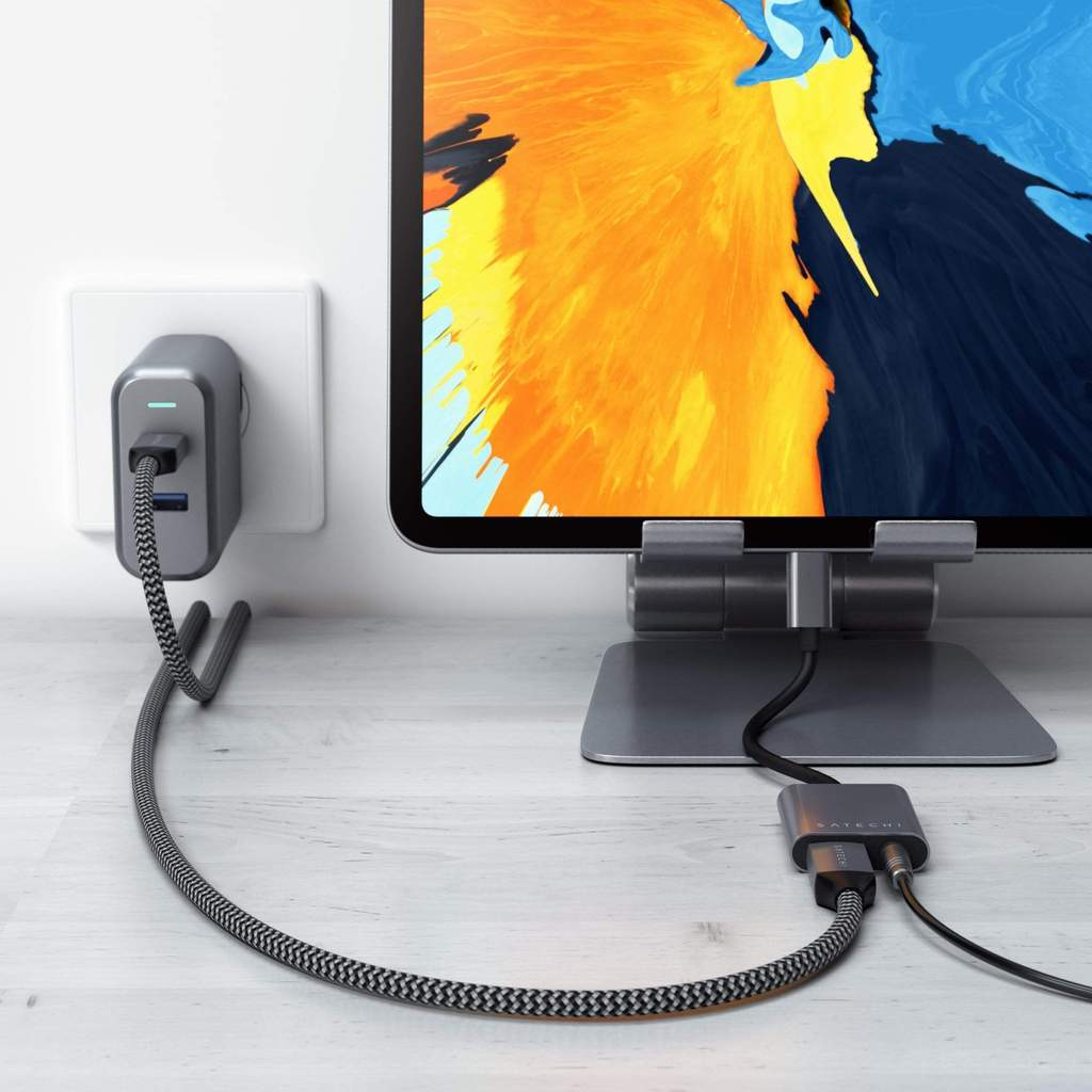 Eine Ladeeinrichtung mit einem grauen Satechi-Adapter, der mit einem Tablet und einer Steckdose verbunden ist.