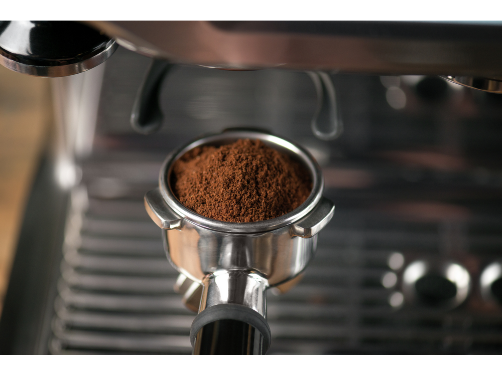 Portafiltro de máquina de espresso lleno de café molido.