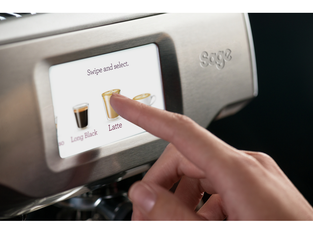 Un dedo toca la opción latte en la pantalla de una máquina de café.