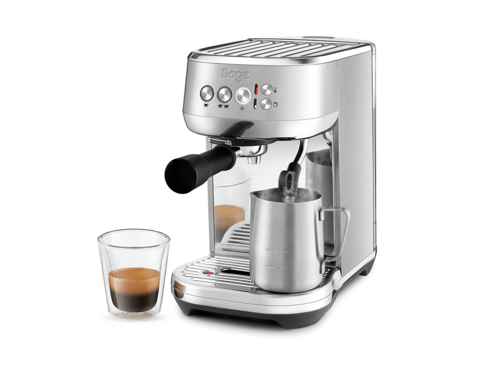 Cafetera espresso plateada con taza de café y jarra espumadora.